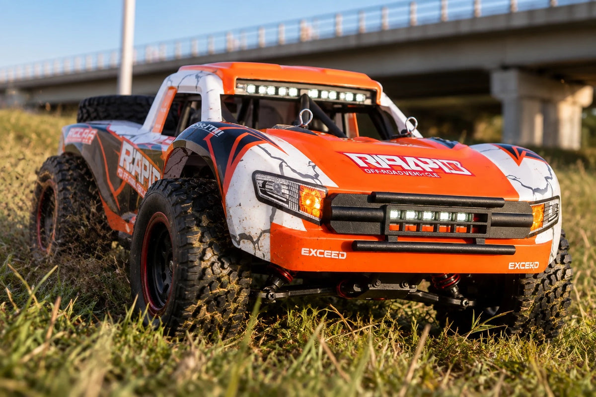 Trophy truck télécommandé Rapid 4×4 1/16 de trois quarts avant dans l'herbe, phares et barre de LED allumés